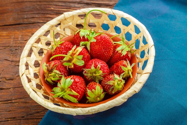 Fresas grandes frescas sobre una mesa de madera en un plato de mimbre. en una servilleta azul. Foto horizontal