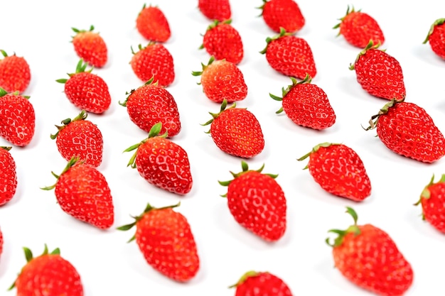 Las fresas de lujo frescas están dispuestas en fila y columna con luz de estudio en el fondo blanco