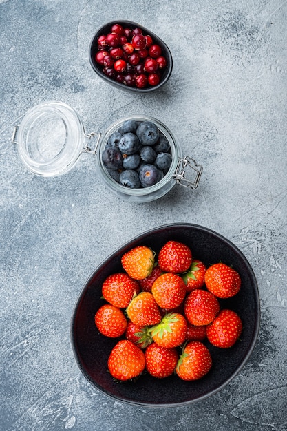 Fresas maduras, arándanos y arándanos en un tazón y jarra, endecha plana