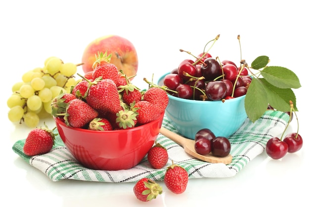 Fresas maduras y bayas de cereza en cuencos, uvas y manzanas aisladas en blanco