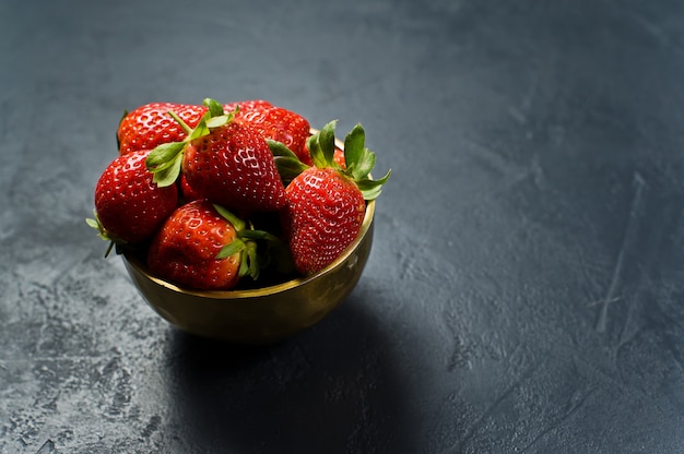 Fresas maduras en un cuenco dorado.