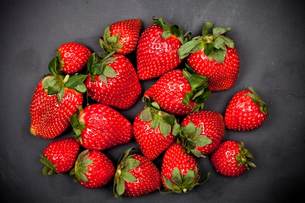 Fresas maduras frescas en fondo negro.