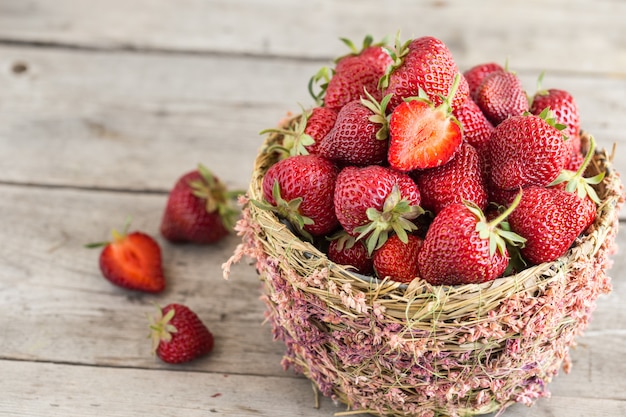 Fresas maduras en una hermosa canasta sobre madera