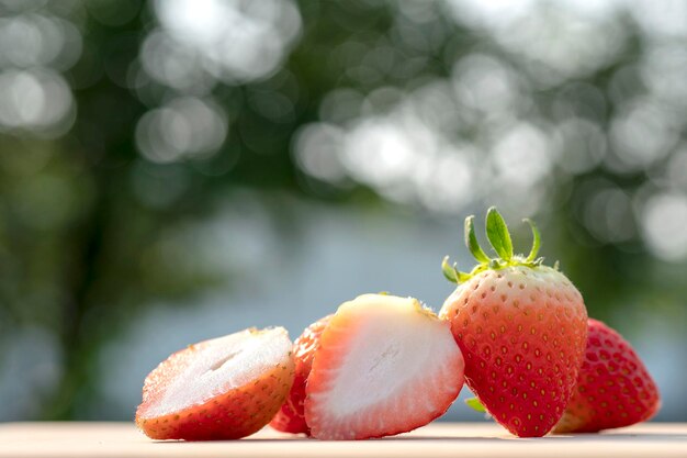 Foto fresas maduras jugosas en la mesa de madera en el jardín con fondo borroso