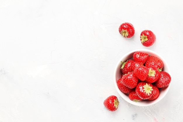 Fresas maduras jugosas en un recipiente sobre un fondo claro. Vista superior