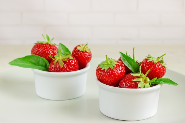 Fresas maduras y menta en un recipiente sobre una mesa