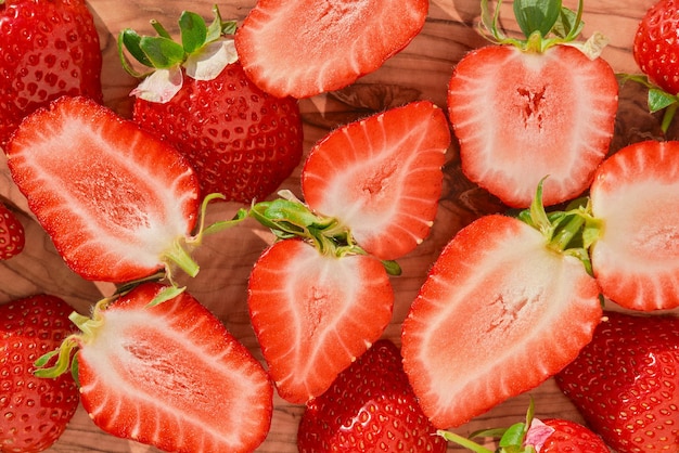 Fresas maduras y mitades de bayas en una mesa de madera idea de la vista superior de la cosecha de bayas de temporada para el fondo de fresas o la preparación de postres