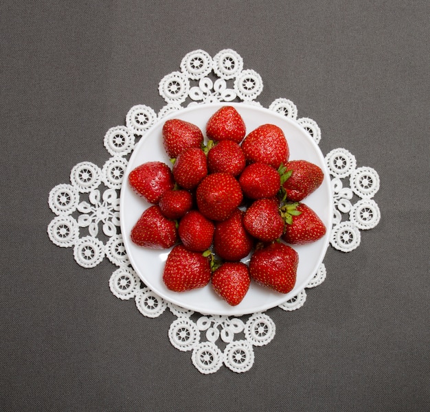 Fresas maduras en un plato sobre un fondo gris, vista superior