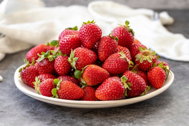 Fresas maduras sobre un fondo oscuro Fresas frescas en el plato Alimentos orgánicos de cerca