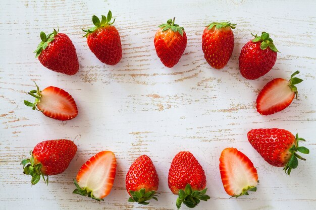 Fresas maduras en la superficie del tablero de madera blanca. Patrón de bayas. Vista superior. Endecha plana con espacio de copia.