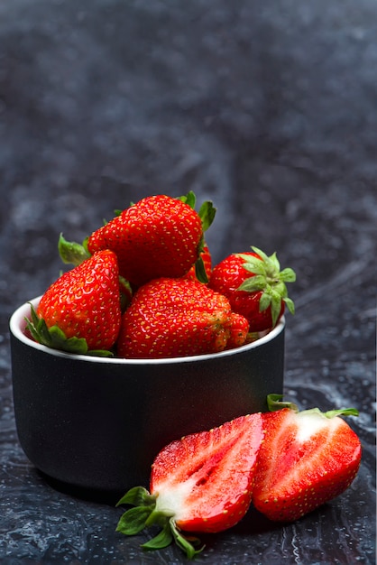 Fresas en mármol negro fresas maduras en un platillo sobre un fondo negro lugar para insertar texto