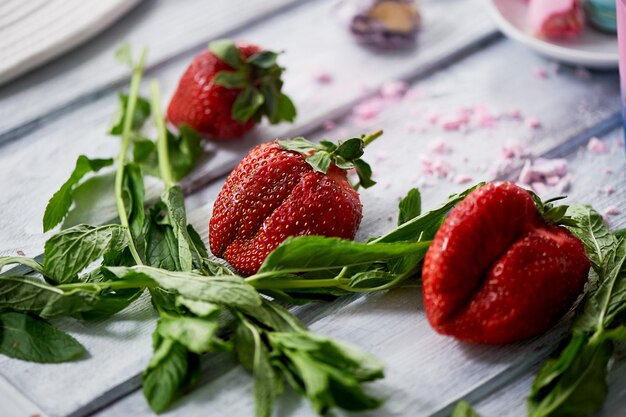 Las fresas y la menta fresca están en el fondo tablas de madera clarasVitaminas frescas