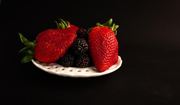 Fresas y moras en un plato blanco.