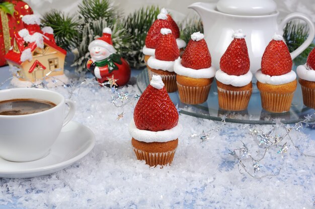 Fresas con nata montada en forma de gorro navideño sobre muffin