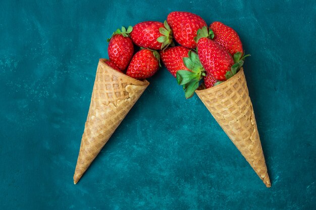 Fresas orgánicas maduras en conos de helado de waffle, imitación vertida