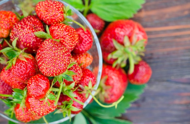 Fresas orgánicas maduras en un jarrón de vidrio sobre una mesa de madera