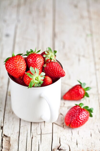 Fresas orgánicas rojas en taza de cerámica blanca.