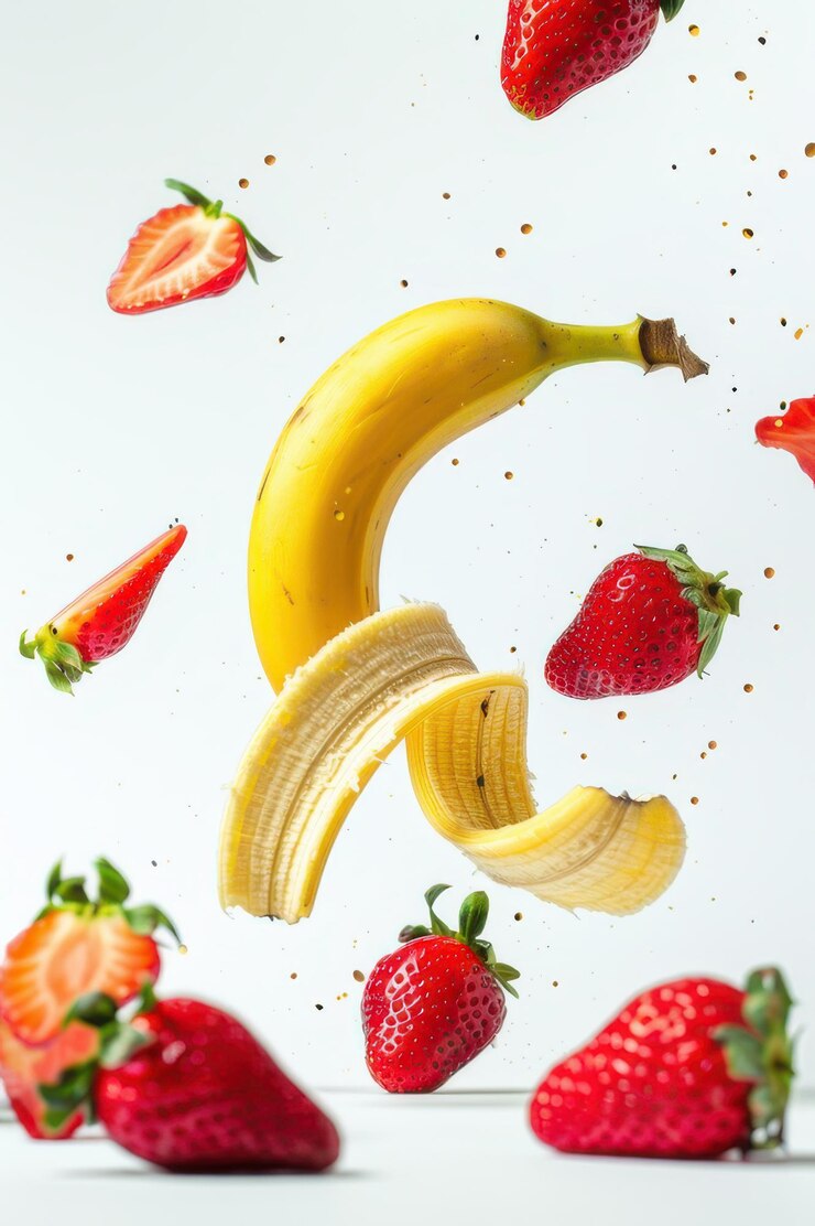 Fresas y plátanos flotantes enteros y cortados en rodajas sobre un fondo blanco que capturan la frescura y los colores vibrantes