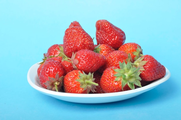 Fresas en un plato sobre un fondo azul.