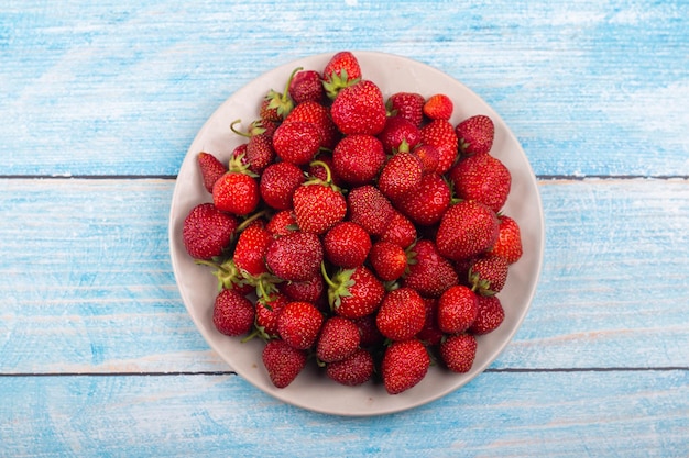 Fresas en un plato sobre un fondo de madera azul