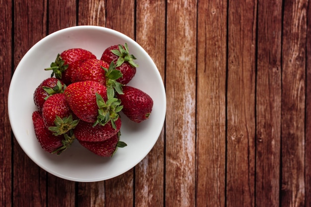 Fresas en un plato sobre una mesa de madera