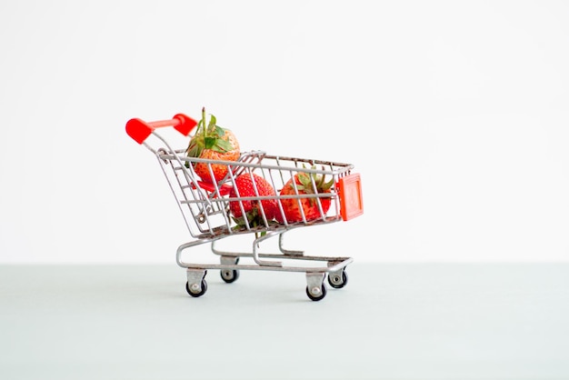 Foto fresas de primer plano en el carrito del carrito de compras que lleva la fresas con fondo aislado