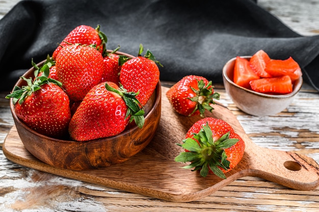 Fresas en un recipiente de madera sobre una tabla de cortar