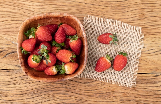 Fresas en un recipiente sobre mesa de madera