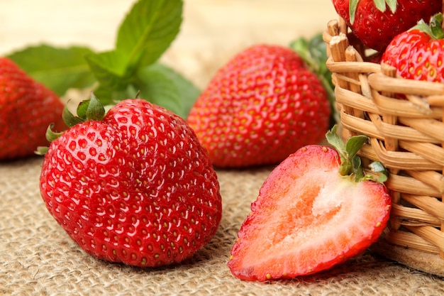 Fresas rojas en una canasta de mimbre sobre una mesa de madera natural