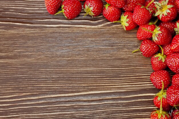 Fresas rojas frescas sobre un fondo de madera marrón