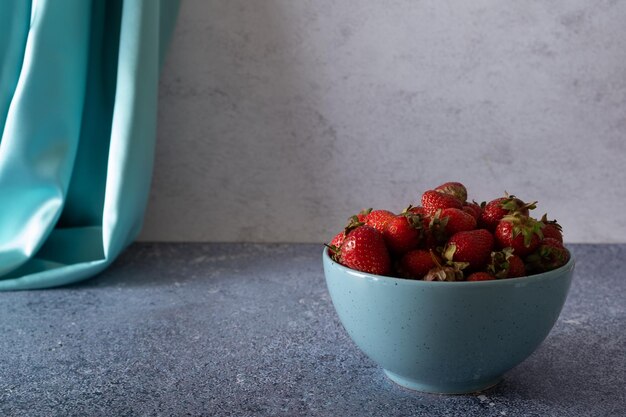 Fresas rojas de jardín maduras en plato sobre mesa de piedra oscura