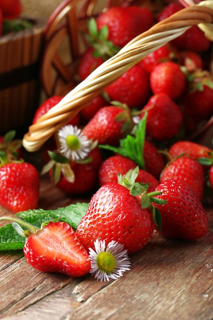 Fresas rojas maduras en cesta de mimbre sobre fondo de madera