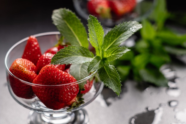 Fresas rojas maduras frescas en un recipiente de vidrio en negro