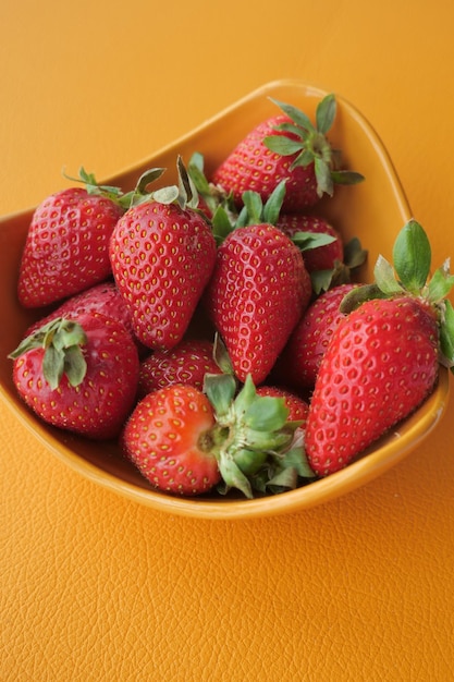 Fresas rojas maduras en un recipiente sobre la mesa