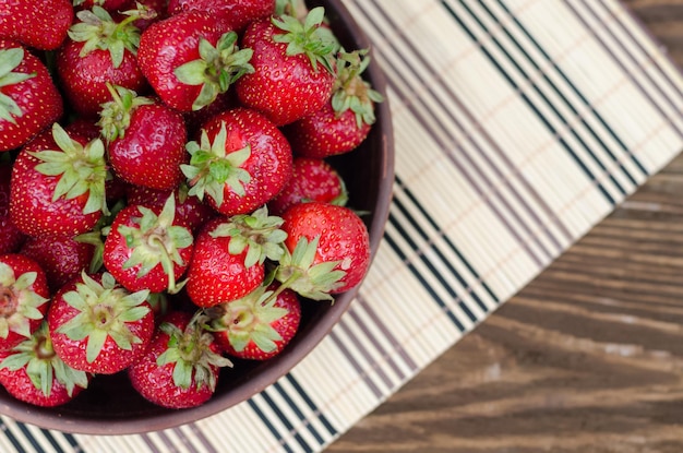 Fresas rojas maduras sobre mesa de madera