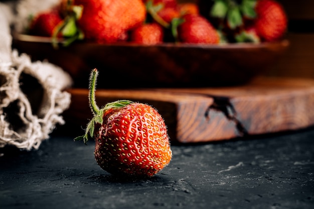 Fresas rojas sobre un tablero oscuro.