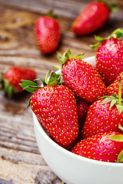 Fresas rojas en un tazón sobre un fondo de madera