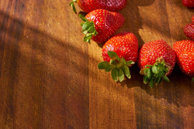 Fresas en una tabla de cortar de madera con fondo de madera