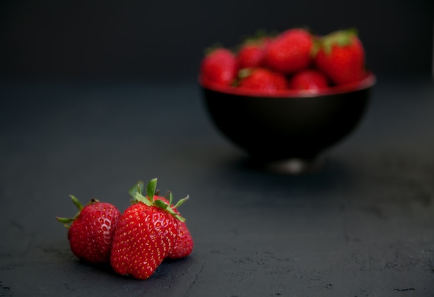 Fresas en un tazón negro y en una superficie negra