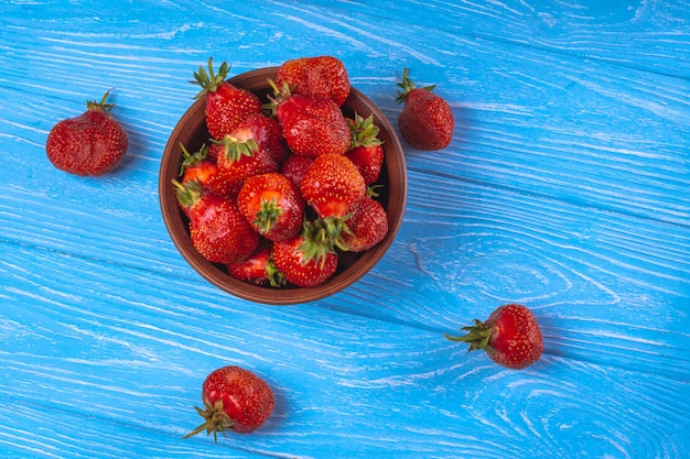 Fresas en un tazón sobre una superficie de madera azul