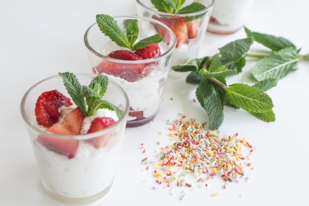 Fresas de temporada con crema y menta en copa de cristal.