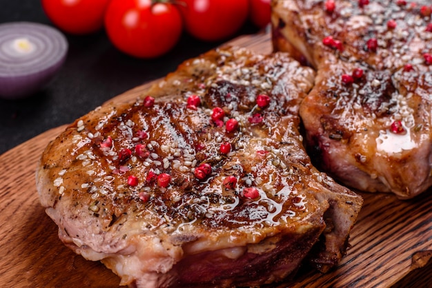 Fresca deliciosa carne jugosa en los huesos con verduras y especias. Parrilla de carne de cerdo jugosa en mesa oscura