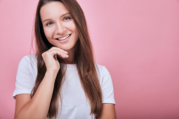 Fresca mujer atractiva puso su mano debajo de su cabeza y sonríe dulcemente.