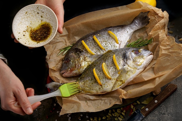 Fresco listo para cocinar pescado dorado crudo con ingredientes y condimentos como romero sal pimienta lima y aceite de oliva vista superior cocinar pescado de mar