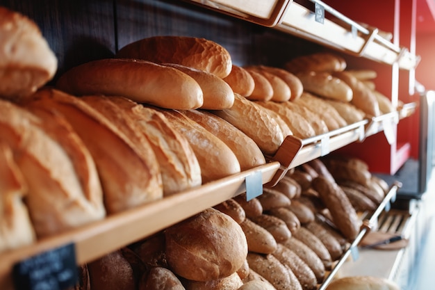 Frescos deliciosos panes de pan en fila en los estantes listos para la venta. Panadería interior.