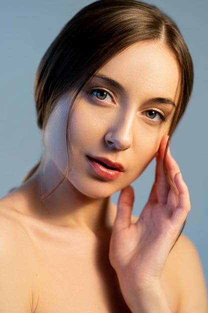 Frescura de belleza Dermatología femenina Salud de la piel Procedimiento facial Retrato de mujer atractiva joven pacífica con cara radiante hermosa aislada en azul