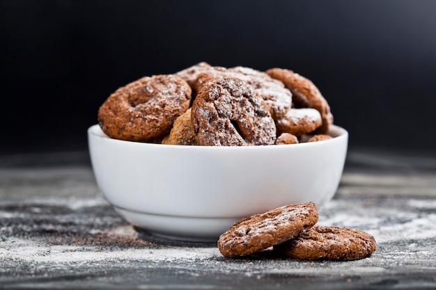 Fresh cozido biscoitos de chocolate e biscoitos de aveia com monte de açúcar em pó em tigela branca