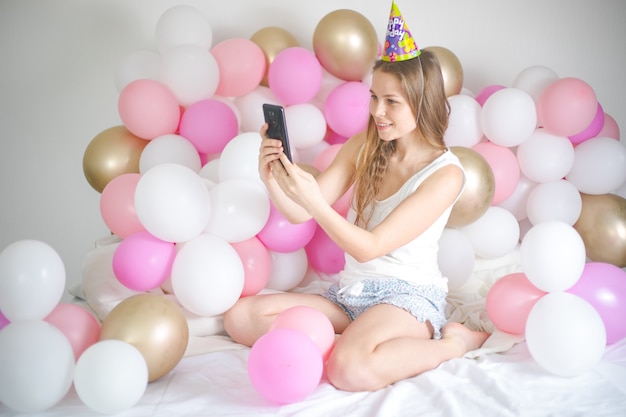 freudige Frau, die lächelt und Selfie auf Handy mit Ballon nimmt