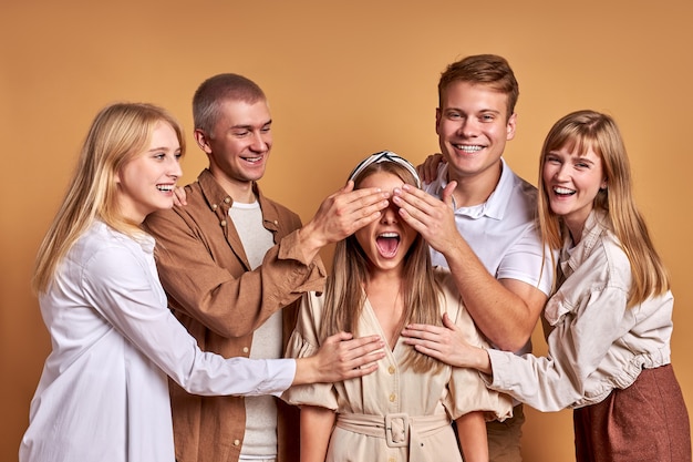 Freudige Freunde haben Spaß, lachen zusammen isoliert auf braunem Studiohintergrund. glückliche Zeit verbringen