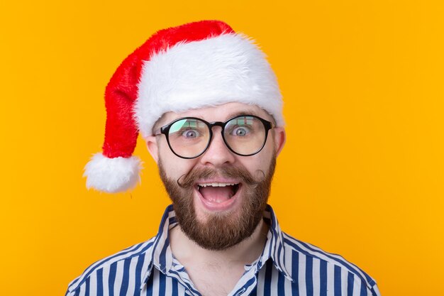 Freudiger verrückter süßer junger Hipster-Mann in der roten Weihnachtsmann-Hutaufstellung